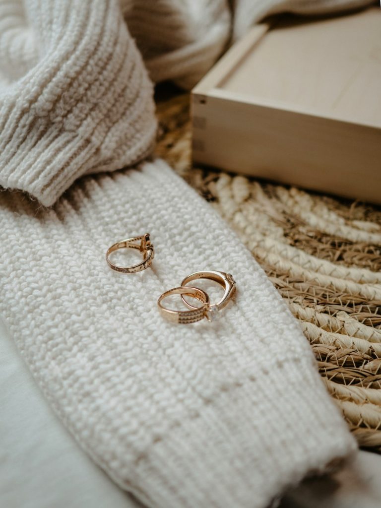 a pair of gold rings sitting on top of a white blanket