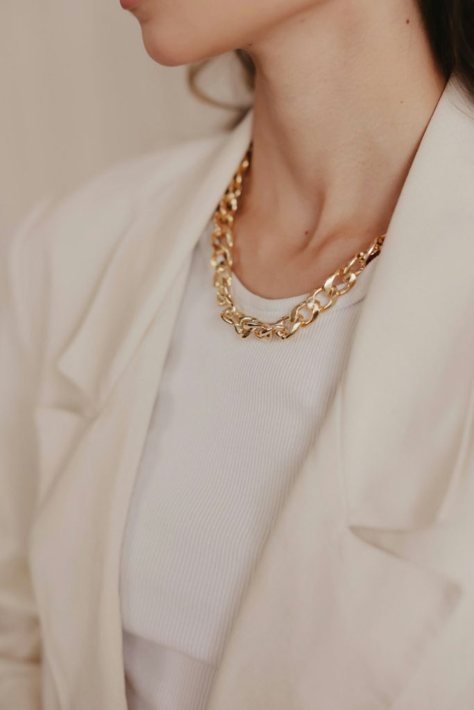 A woman wearing a white jacket and a gold necklace