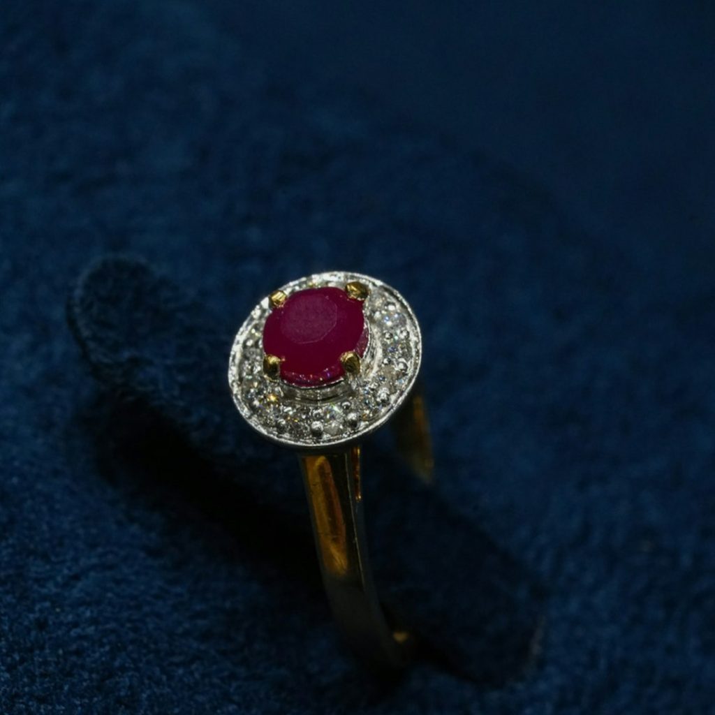 A diamond and ruby ring on a blue velvet surface