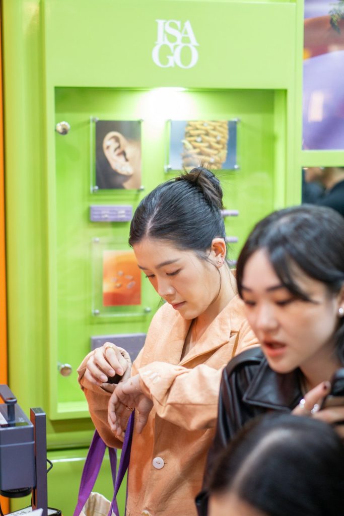 Women look at a smart watch near a display.