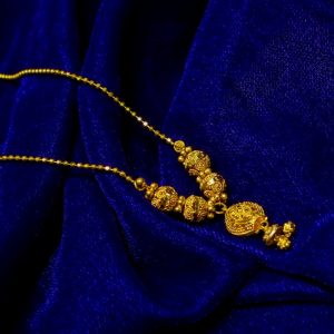 Gold necklace with intricate bead details on blue velvet
