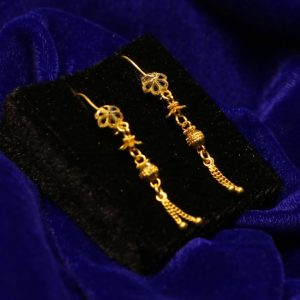 Gold dangle earrings on black velvet display