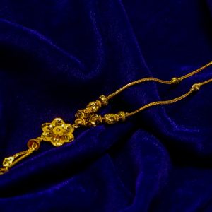 Gold floral pendant necklace on blue fabric