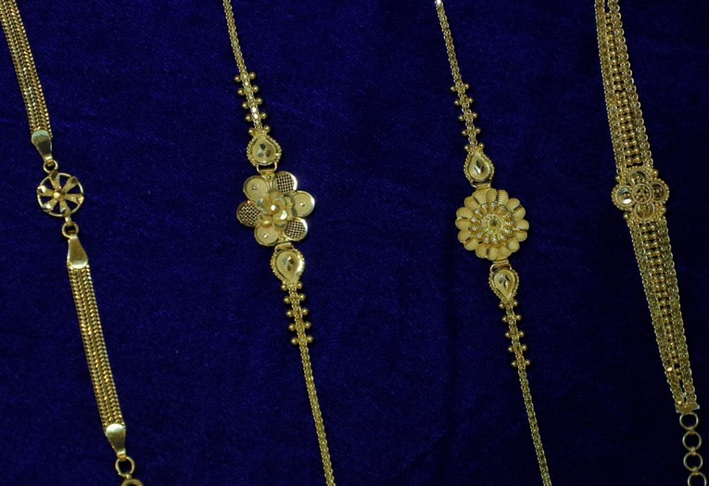Four delicate gold bracelets on blue velvet