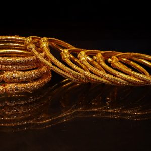 A stack of ornate gold bangles on a dark surface.