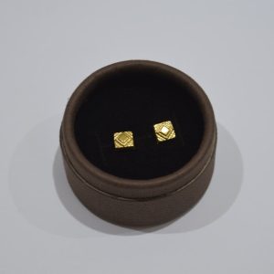 Two small gold square earrings in a box.