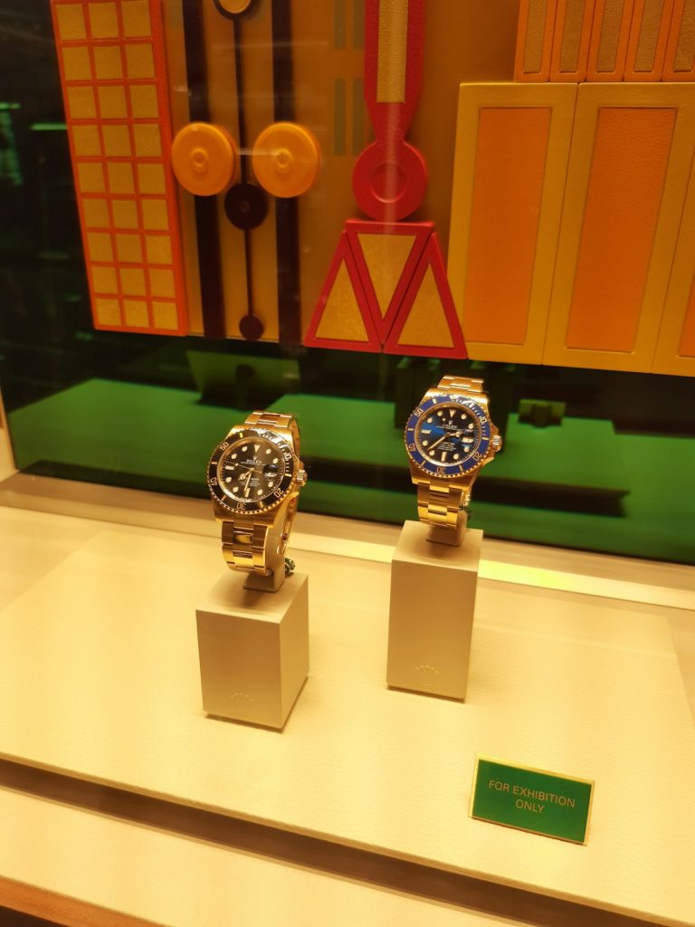 Two luxury watches displayed in a store window.