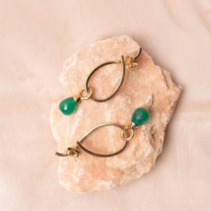 Gold earrings with green gemstones on pink stone