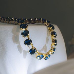 Gold necklace with blue gemstones on white fabric