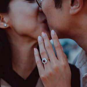 Couple shares a tender kiss, showing engagement ring