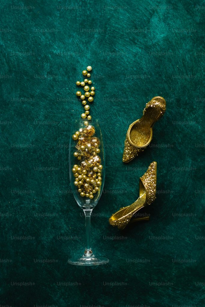 a pair of gold shoes and a wine glass