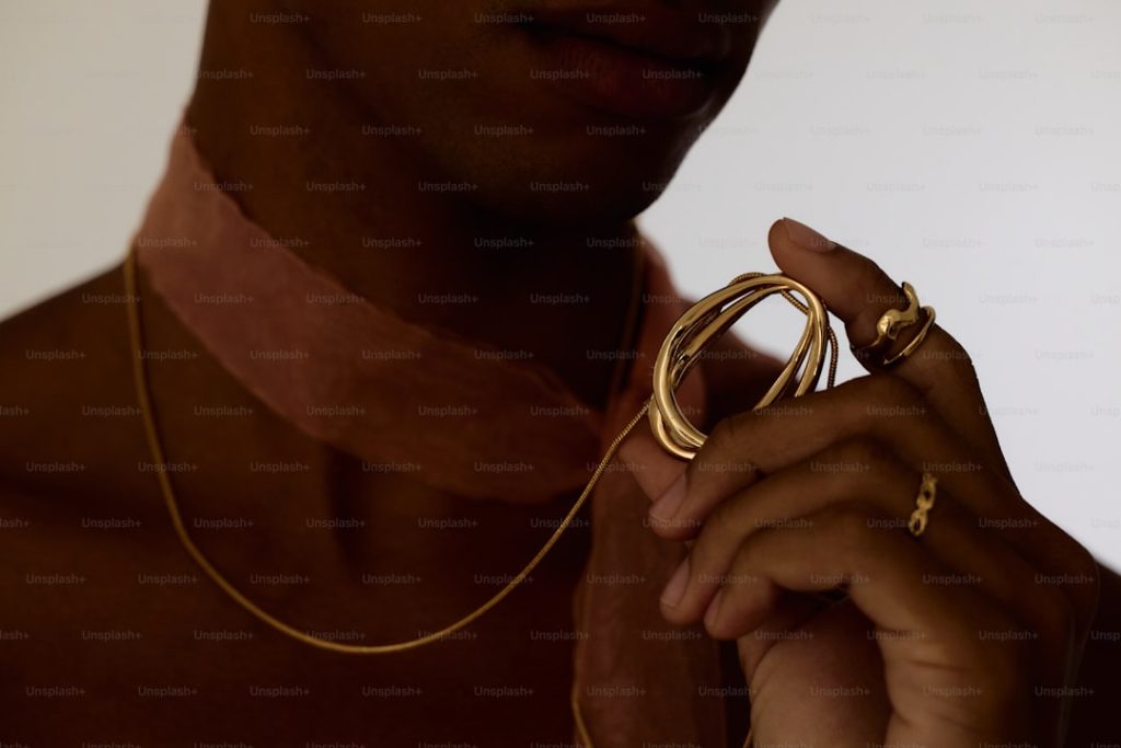 A man wearing a gold necklace holding a gold ring